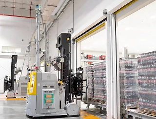 Vehículo de guiado automático (AGV) transportando pallets de productos en un almacén inteligente de Coca-Cola Andina, representando la vanguardia tecnológica en la cadena de suministro.